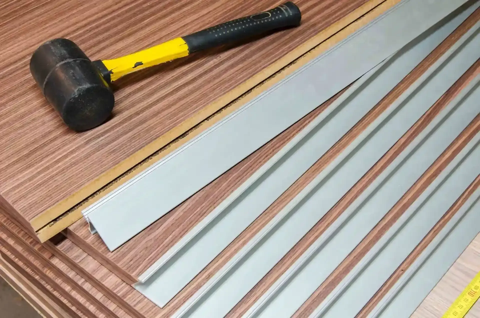 Mazo de goma y tiras de medición sobre láminas de chapa de madera.