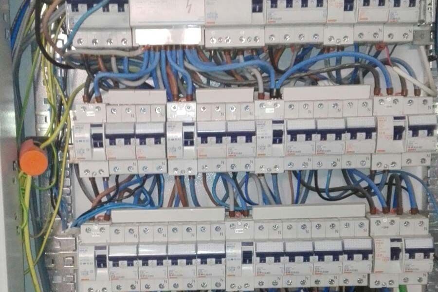 Panel eléctrico con filas de disyuntores y cableado. Cables azules, marrones y grises.