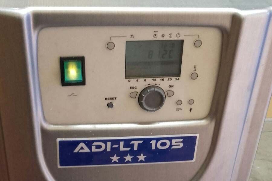 Primer plano de un panel de control con un botón de encendido verde, una pantalla digital que muestra 