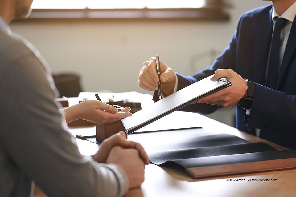 Rechtsanwalt Roland Netzer reicht einem Klienten ein Formular