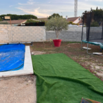 Une piscine est située à côté d'un trampoline dans une cour arrière.