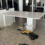 Une grande table blanche est posée sur un sol carrelé dans une pièce.