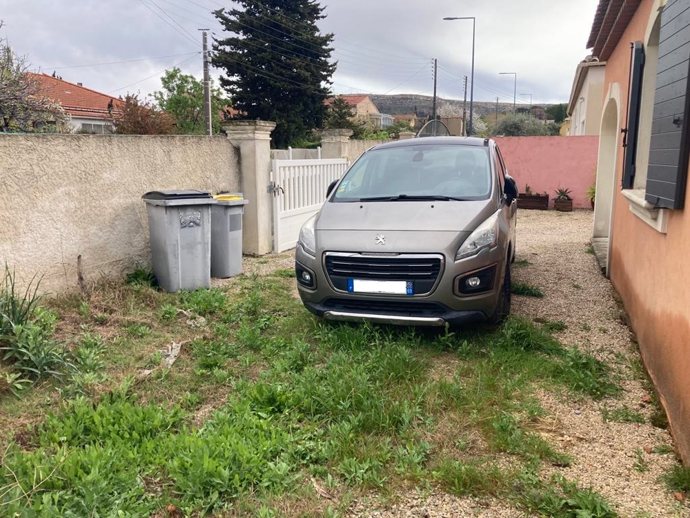 Une voiture est garée dans l'herbe devant une maison