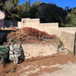 Une brouette est garée devant un tas de terre.
