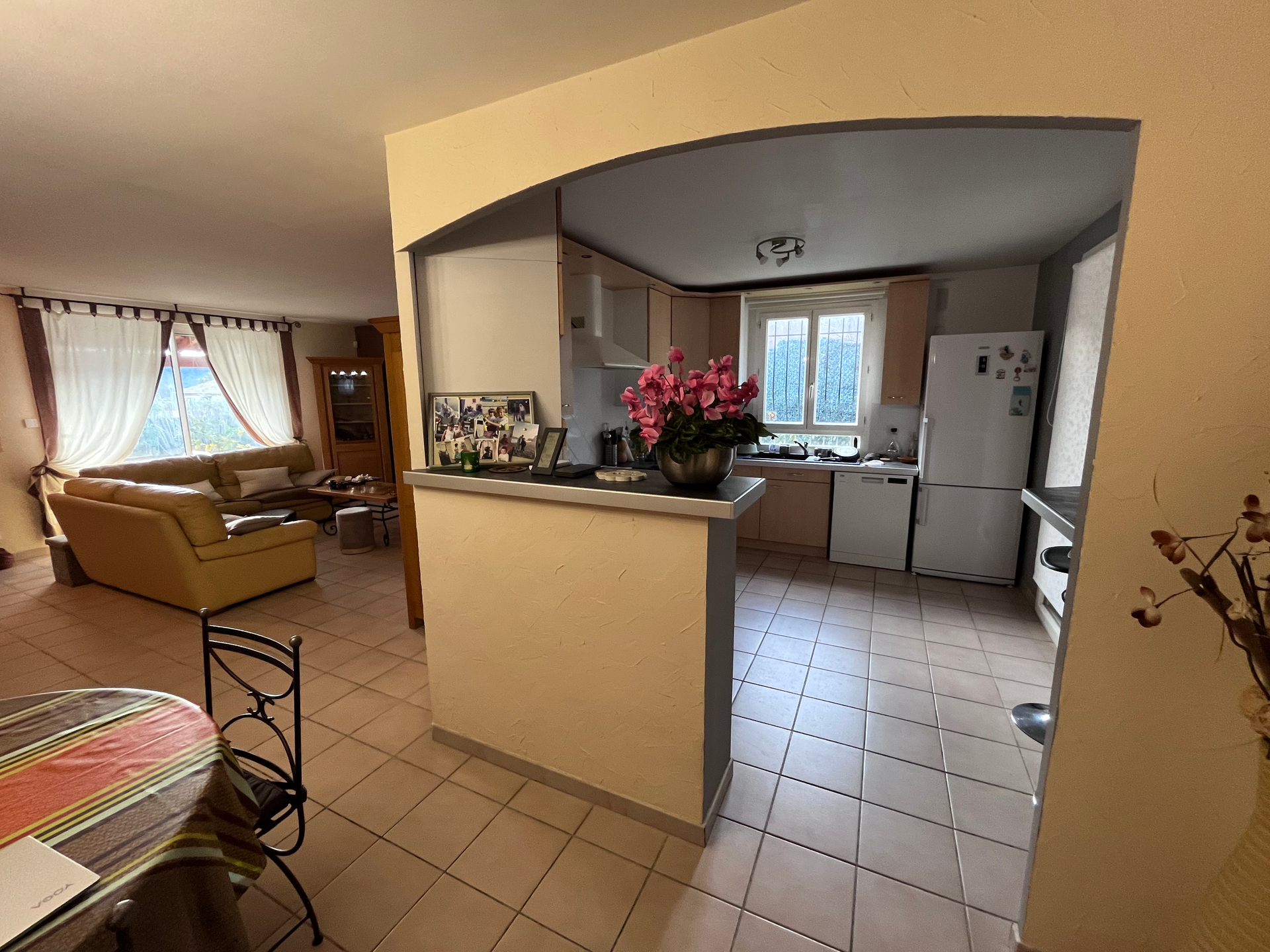 Un salon avec un canapé, une table et des chaises et une cuisine avec un réfrigérateur.