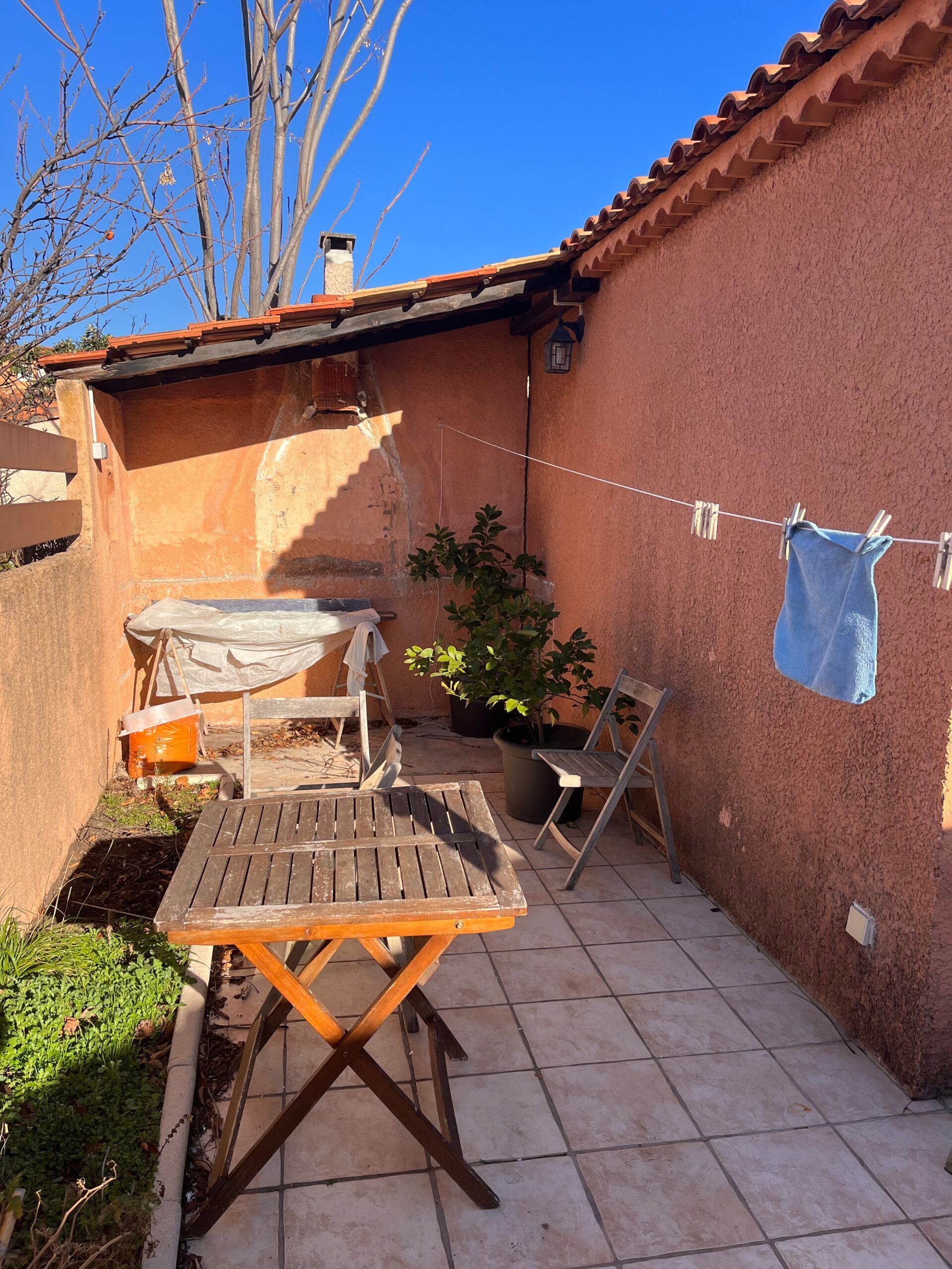 Un patio avec une table et des chaises et des vêtements suspendus sur une corde