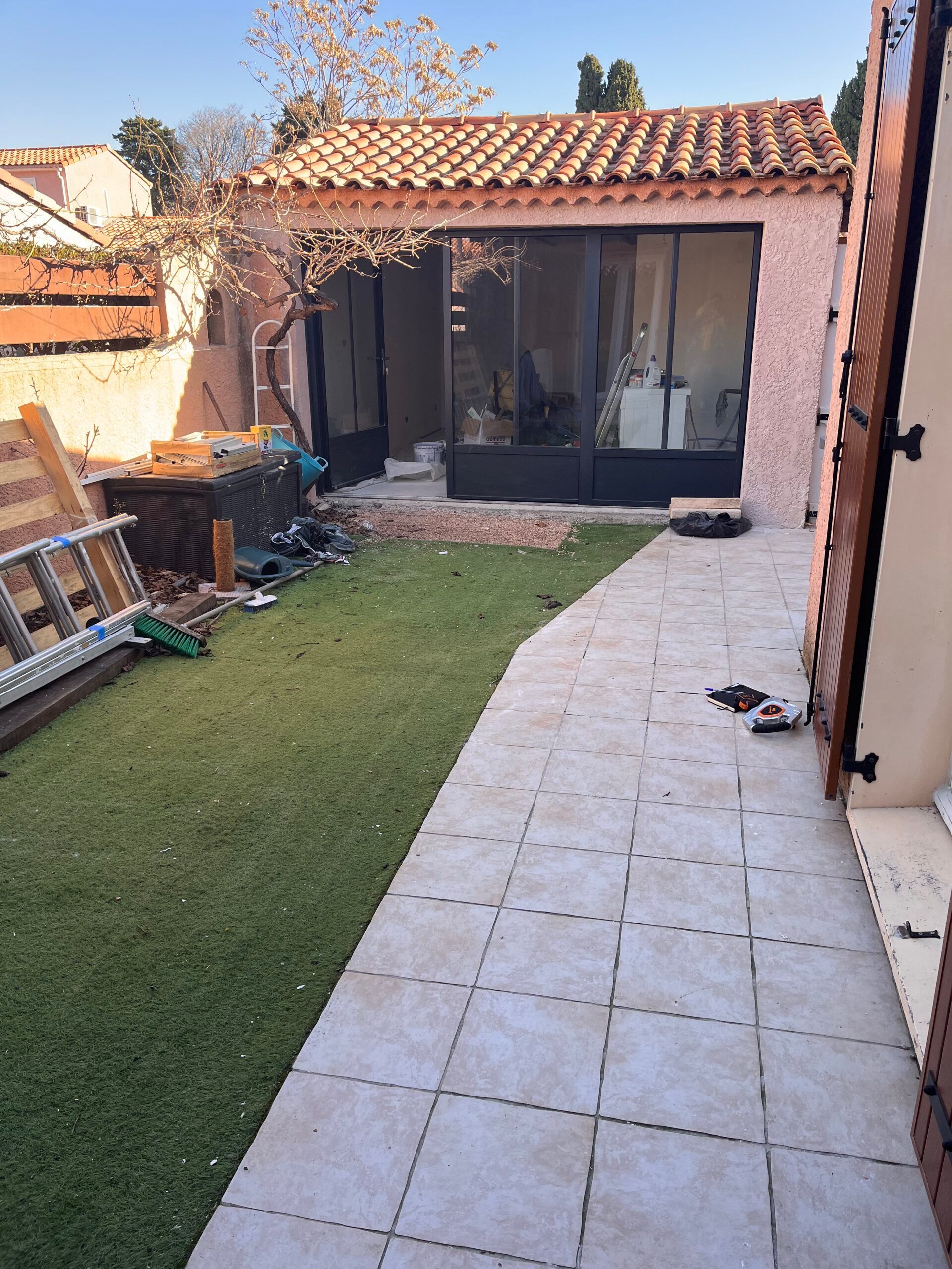 Une échelle est posée sur le trottoir devant une maison.