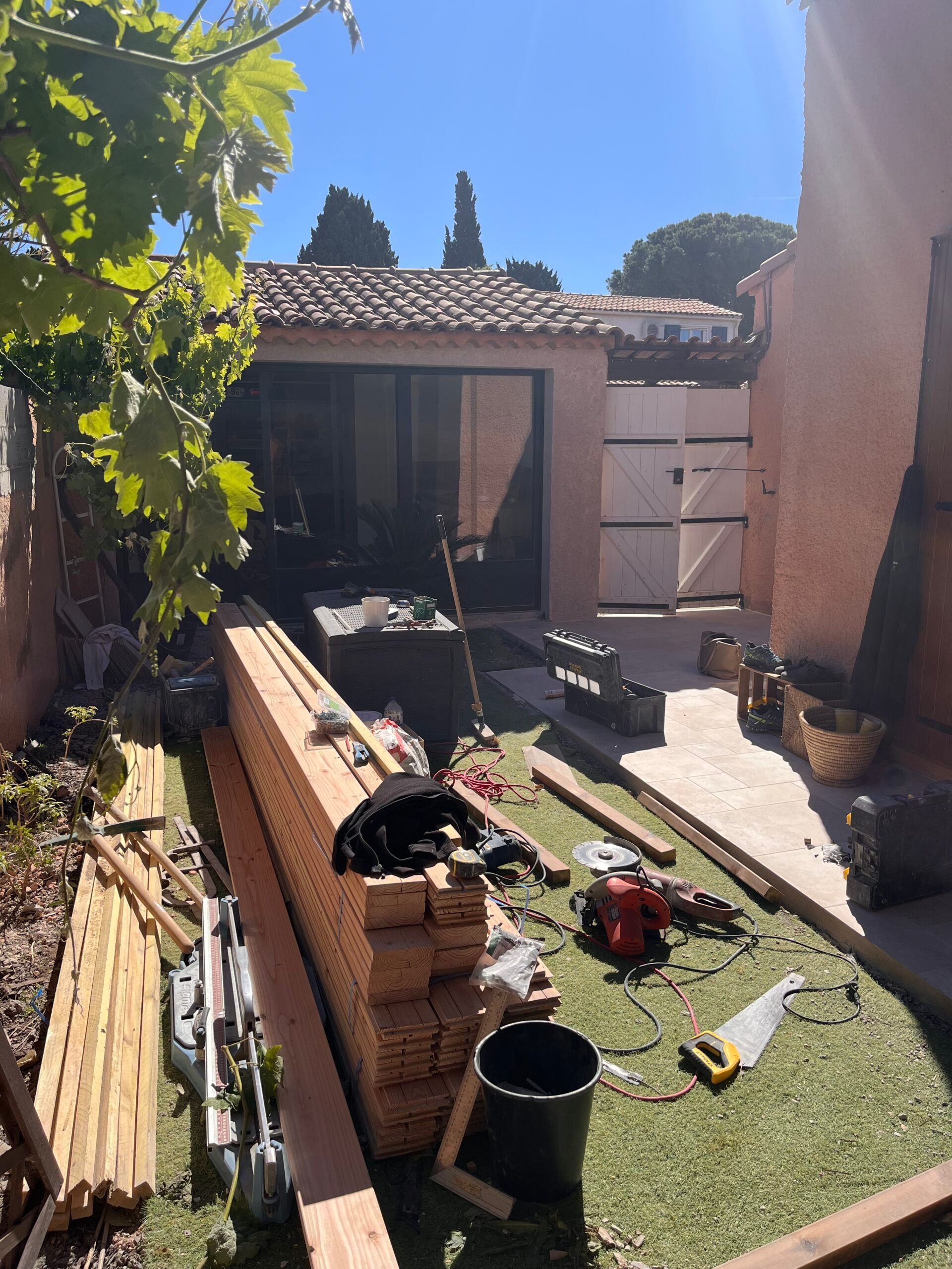 Un tas de bois est posé sur l'herbe devant une maison.