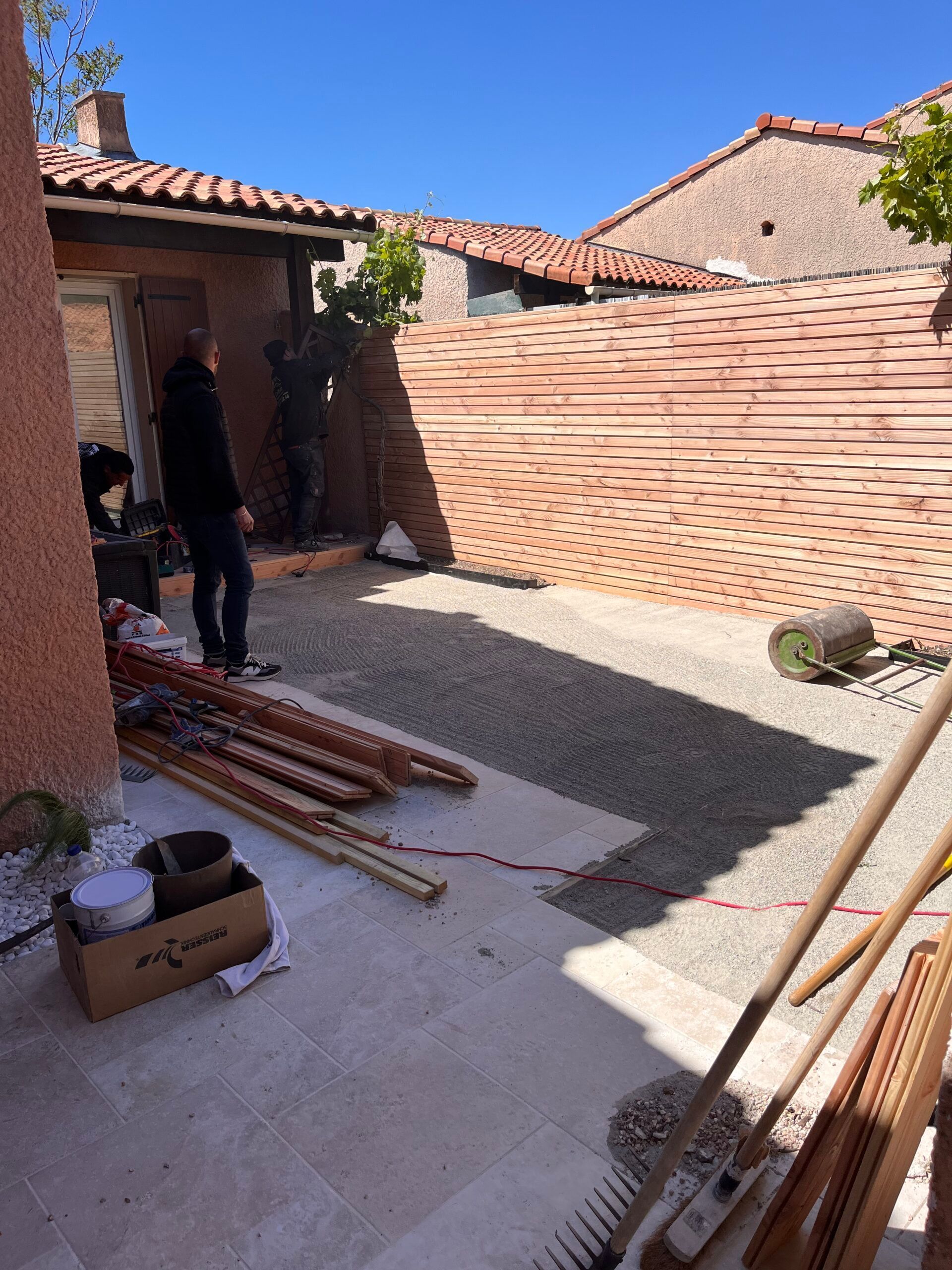 Un homme se tient devant un mur de briques dans une cour arrière.