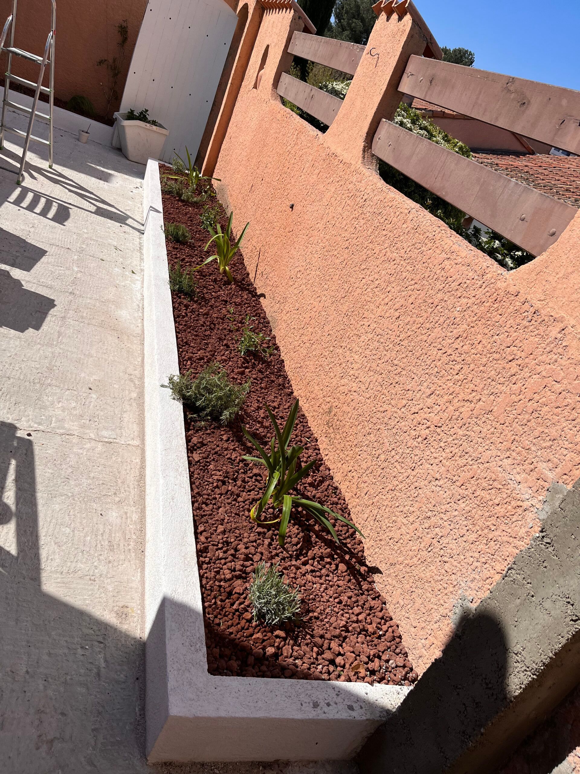 Une jardinière avec des plantes à l'intérieur se trouve à côté d'une clôture.