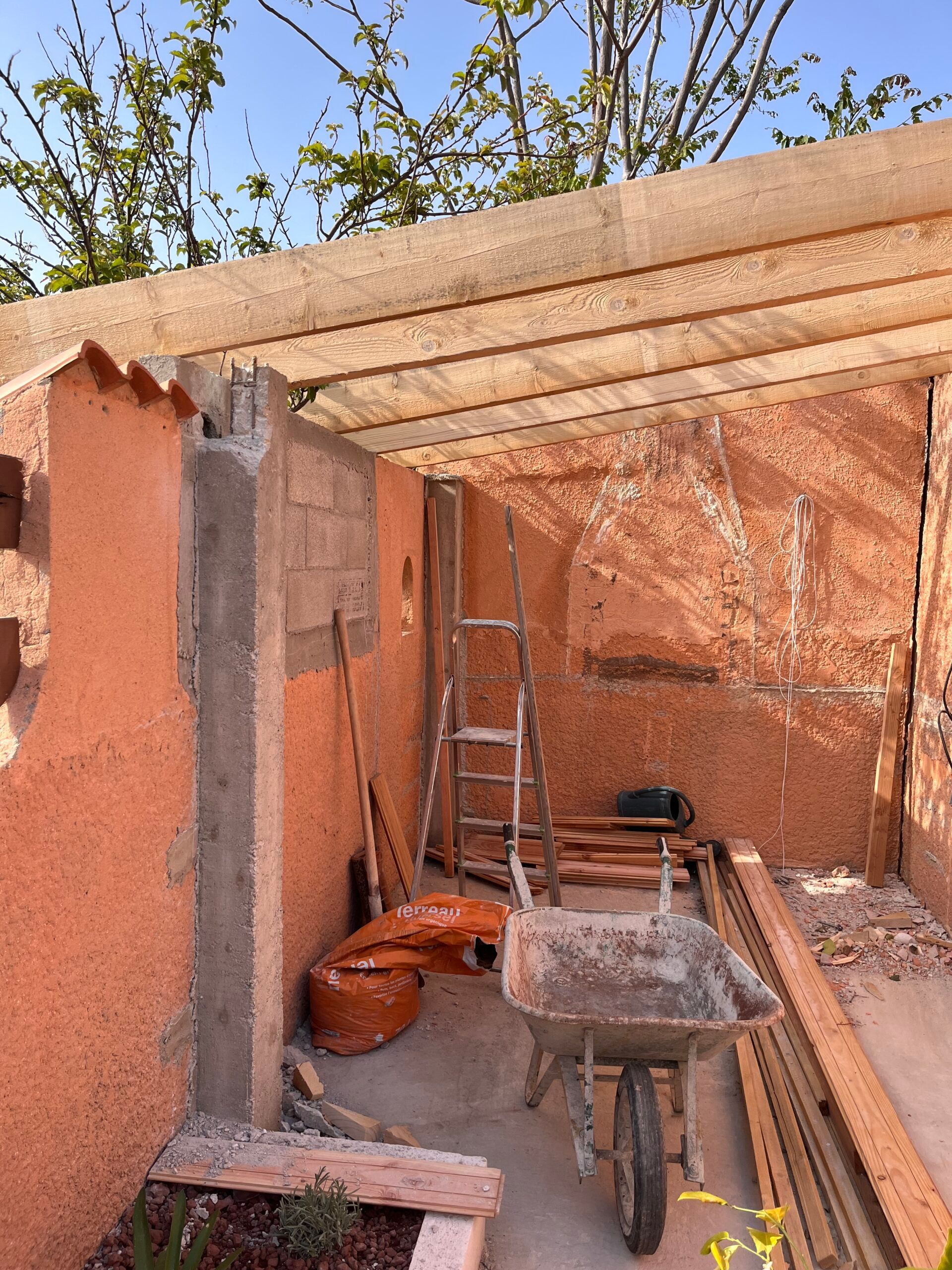 Une brouette est assise devant un bâtiment en construction.