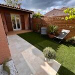 Une petite cour arrière avec une table et des chaises devant une maison.