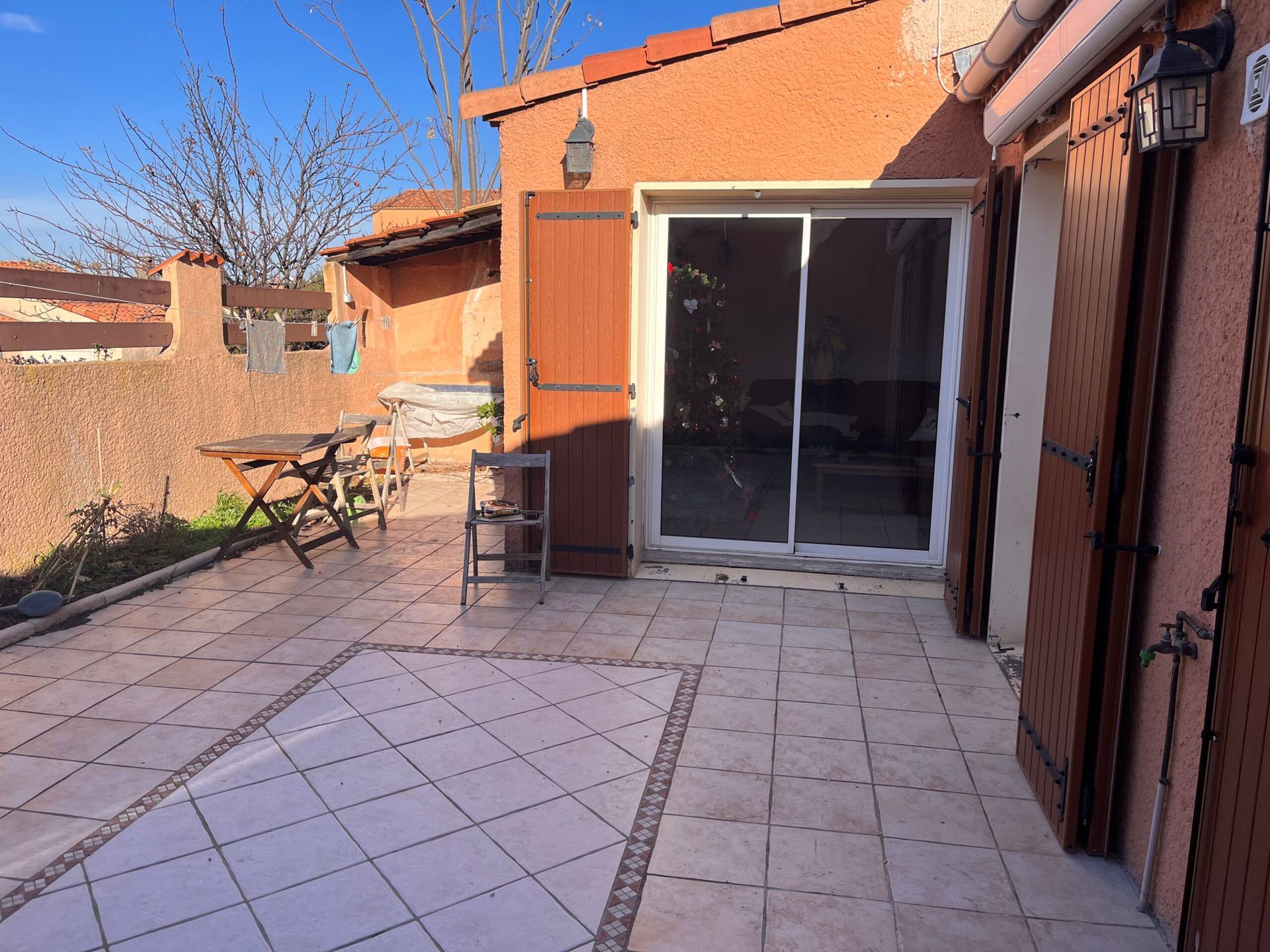 Un patio avec une table et des chaises devant une maison
