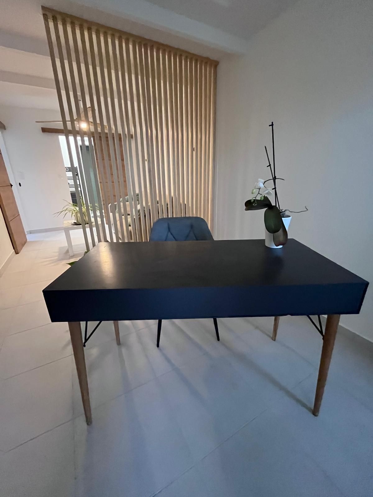 Une table noire avec un vase de fleurs dessus dans une pièce.