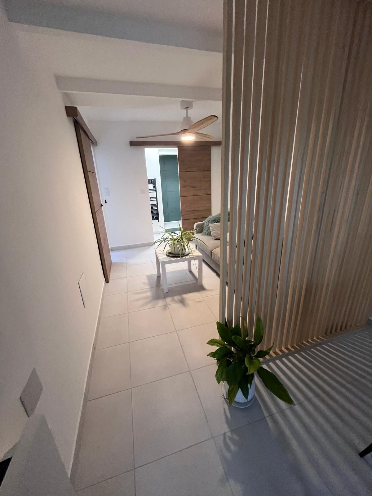 Un salon avec un canapé, une table et un ventilateur de plafond.