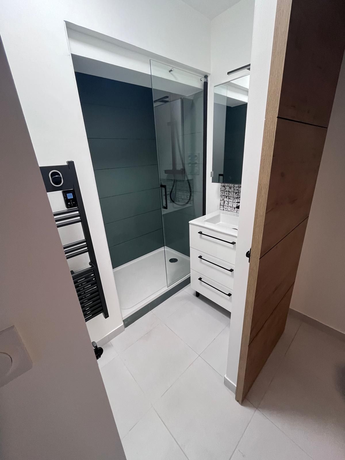 Une salle de bain avec lavabo, douche et miroir.