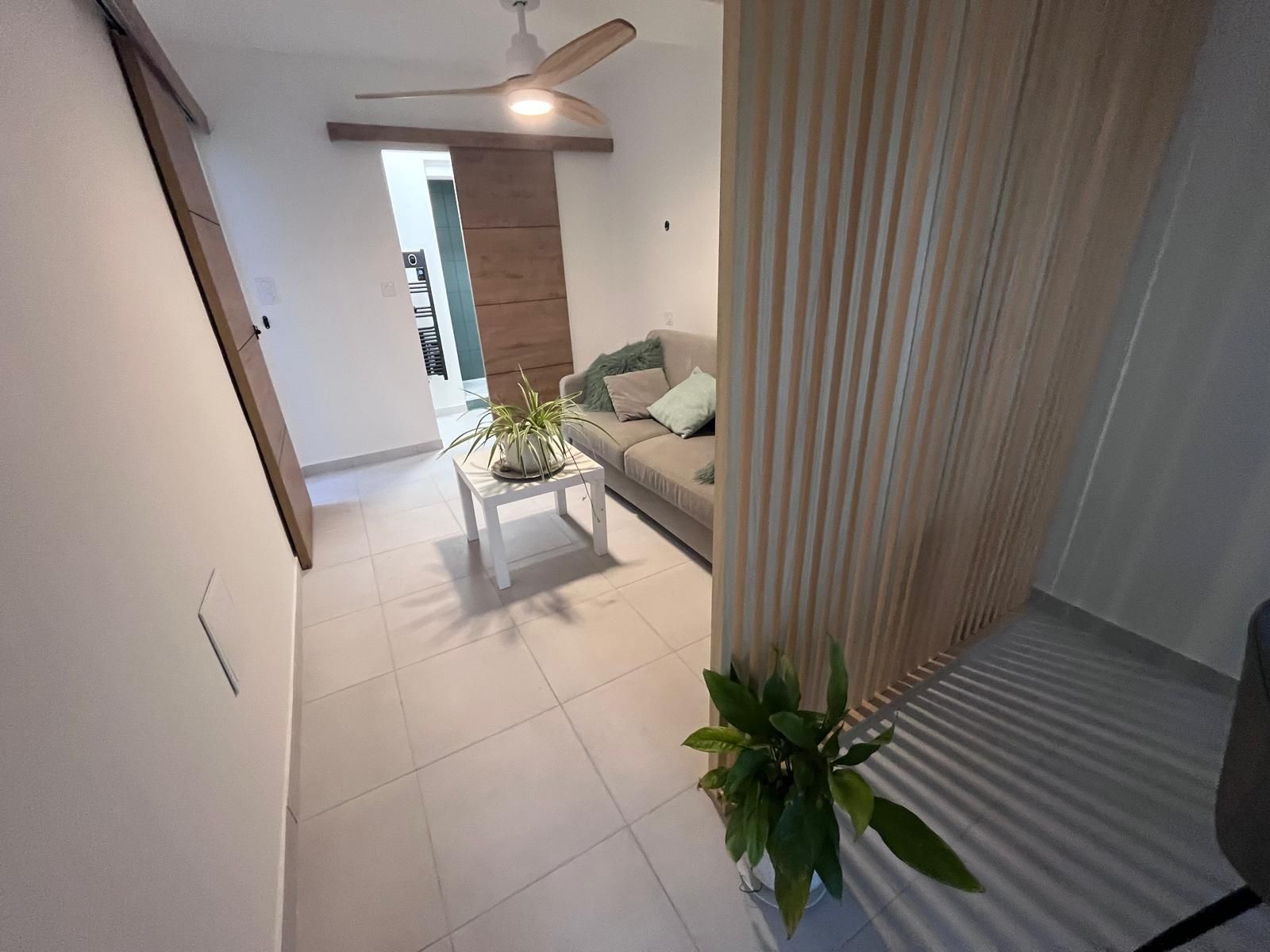 Un salon avec un canapé, une table et un ventilateur de plafond.