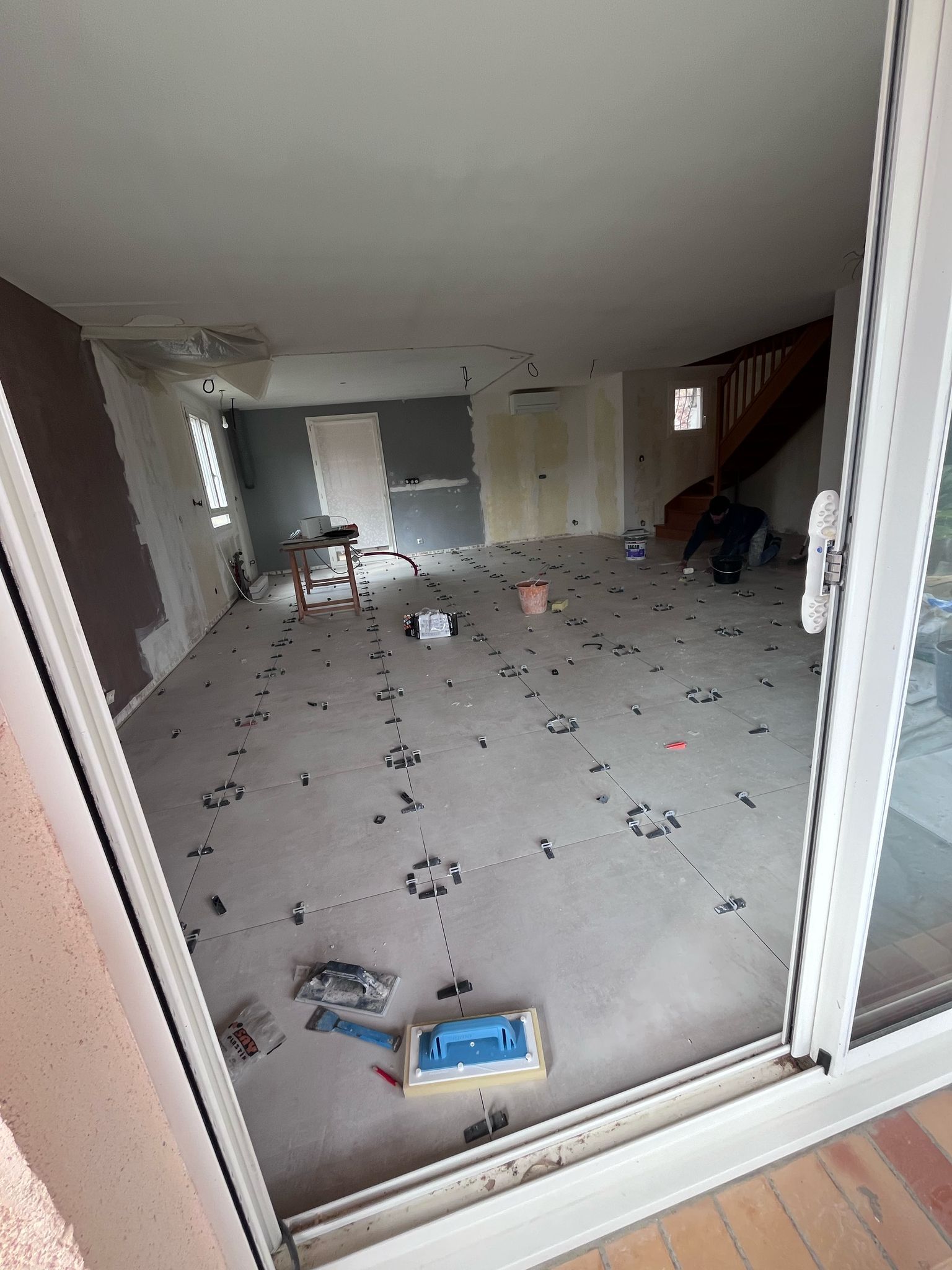 Une pièce avec beaucoup de carrelage au sol et une porte coulissante en verre.