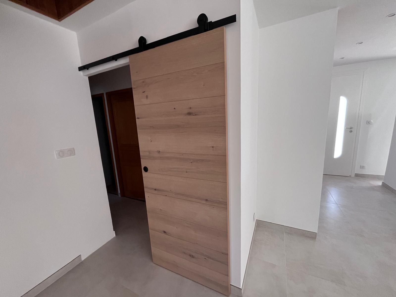 Une porte de grange coulissante est ouverte dans un couloir.