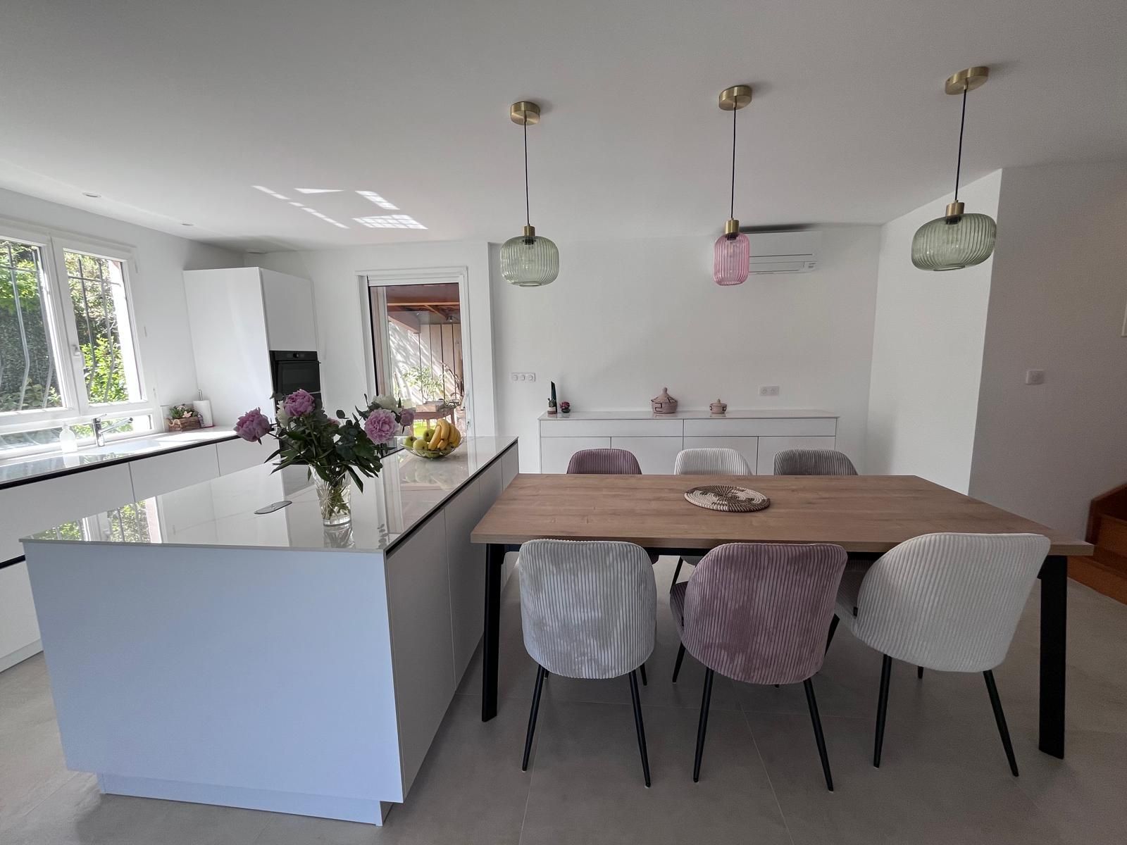 Une cuisine avec une table et des chaises et un vase de fleurs sur le comptoir.