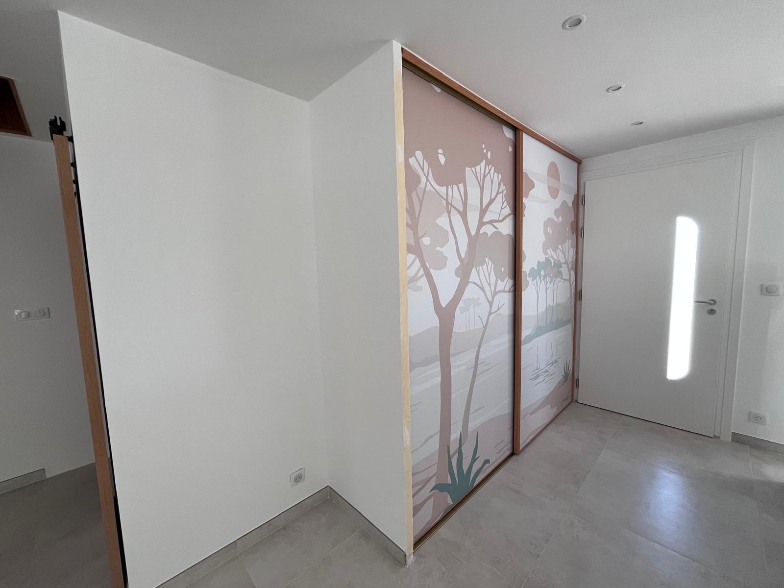 Un couloir avec des portes coulissantes en verre et un tableau au mur.