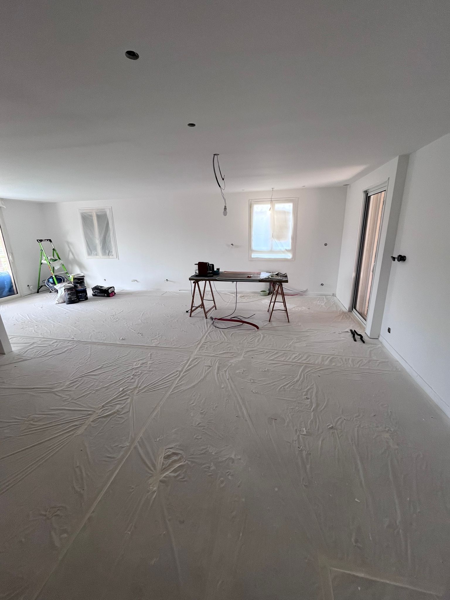 Une grande pièce avec des murs blancs et une table au milieu.