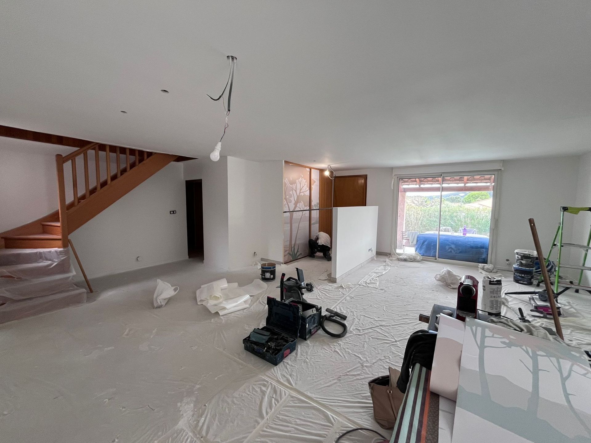 Un salon avec un escalier et beaucoup d'outils au sol.