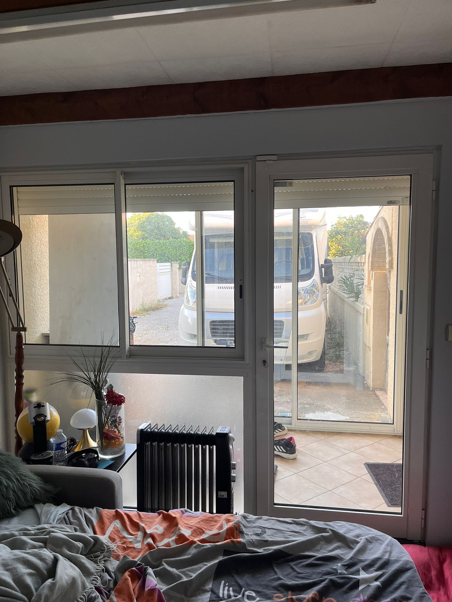 Une chambre avec un lit, un canapé, une lampe et des portes coulissantes en verre.