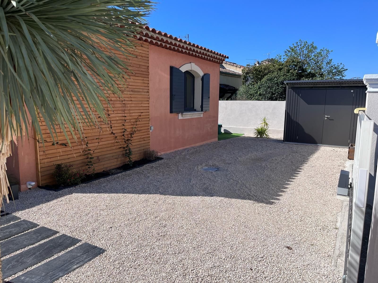 Une maison avec un garage et une allée de gravier devant.