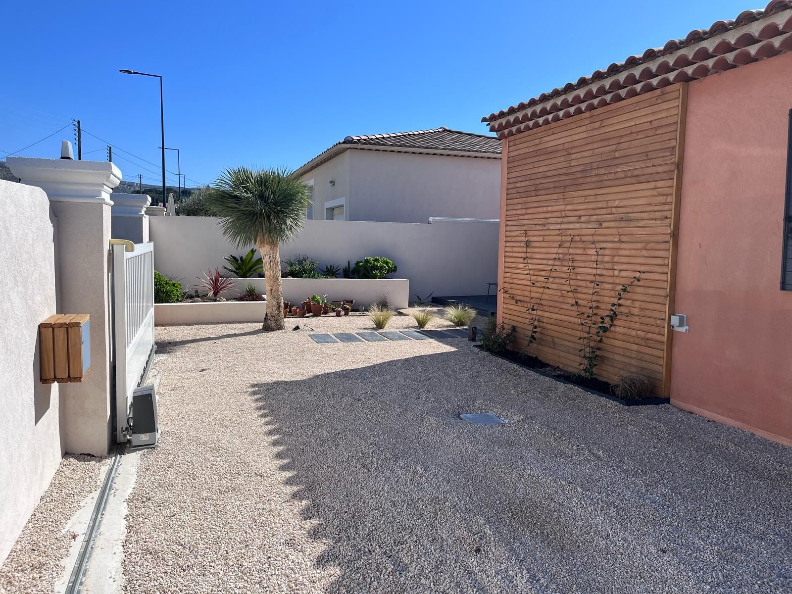 Une allée de gravier menant à une maison avec un mur de briques