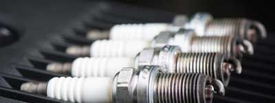 Gros plan sur des bougies d'allumage alignées dans une pièce automobile.