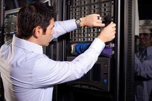 Un homme travaille sur une baie de serveurs, dans un centre de données.