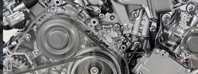 Gros plan sur les composants internes d'un moteur de voiture, montrant en détail les courroies, les poulies et les pièces métalliques.