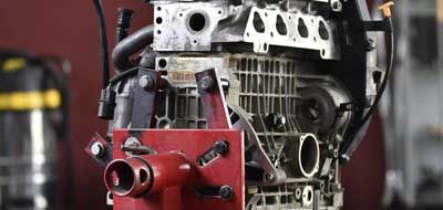 Dans un magasin, un bloc moteur est maintenu par un support métallique rouge.