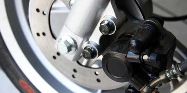 Ensemble de frein à disque de moto avec fourche argentée et étrier noir, gros plan.