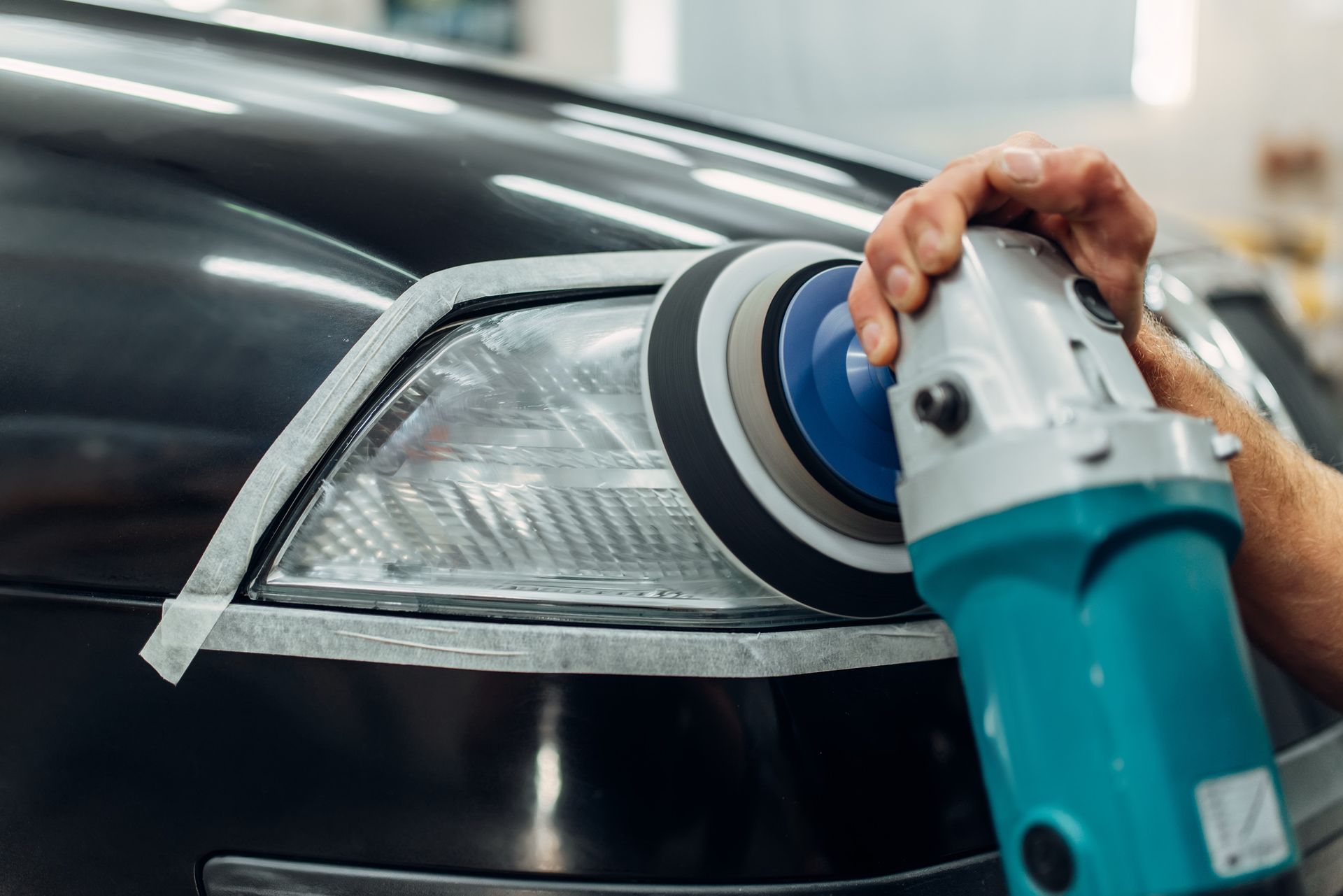 Una persona está puliendo un faro de coche con una máquina.