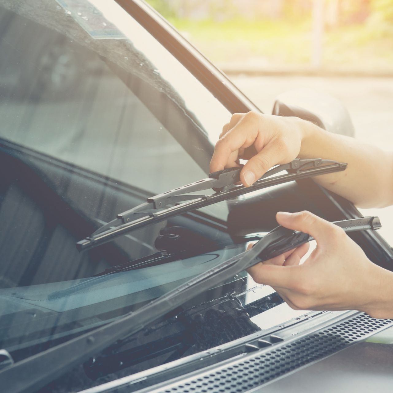 Una persona está limpiando el parabrisas de un coche.