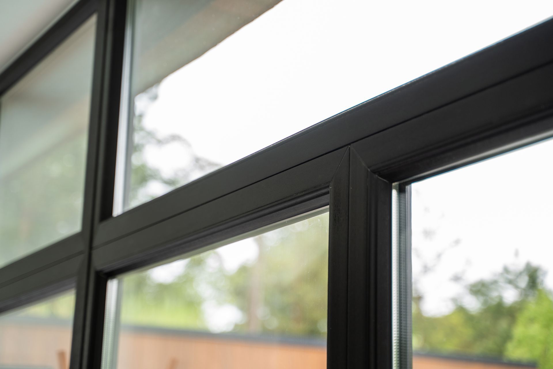 Gros plan sur un cadre de fenêtre noir avec des vitres, vue extérieure floue.