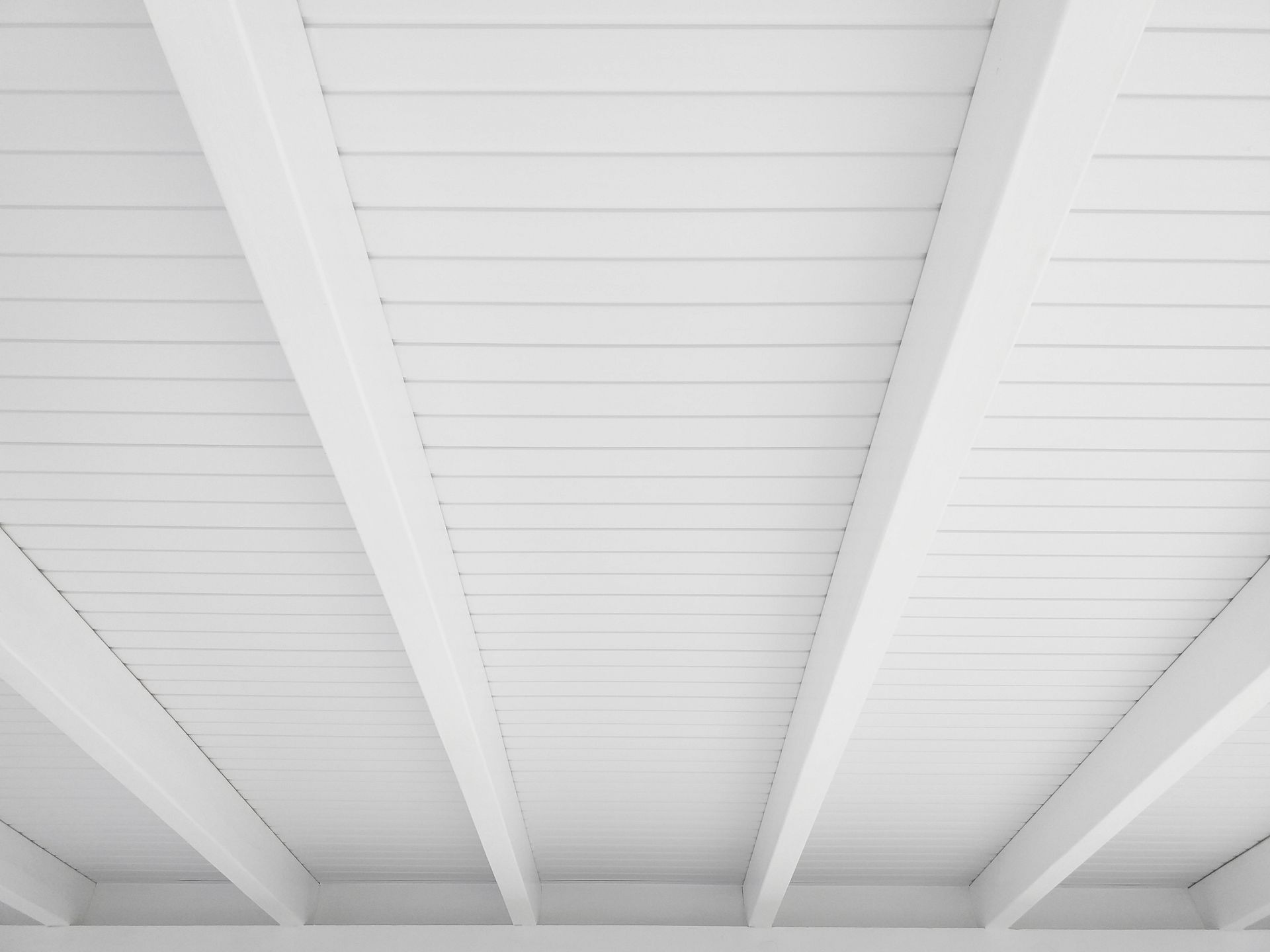 Plafond en bois blanc avec poutres apparentes.