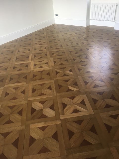 Parquet en bois à motif géométrique répétitif, carrés de bois clair et foncé.