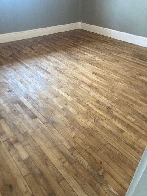 Sol en bois dans une pièce, avec des plinthes blanches et des murs gris.