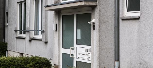 Ein graues Gebäude mit einer weißen Tür und einem Fenster.