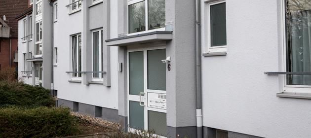 Ein weißes Gebäude mit einer Tür und vielen Fenstern.
