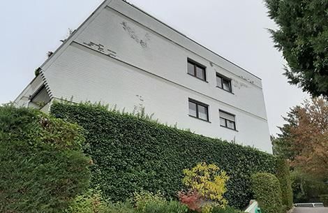 Ein großes weißes Gebäude mit einer Hecke davor