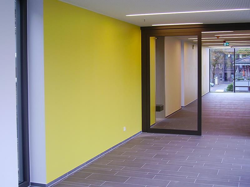 Ein Flur mit einer gelben Wand und einer Glasschiebetür