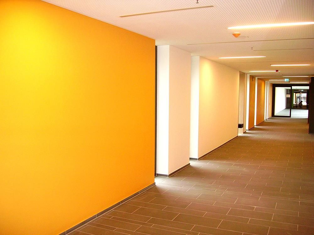 Ein leerer Flur mit orangefarbenen Wänden und weißen Säulen