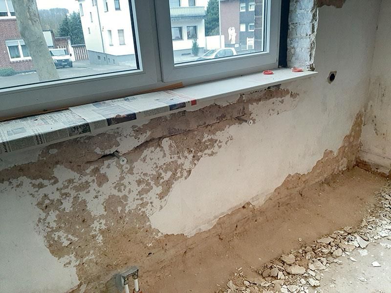 Ein Zimmer mit einem Fenster und viel Schmutz auf dem Boden.