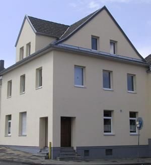 Ein großes weißes Haus mit einem grauen Dach und vielen Fenstern