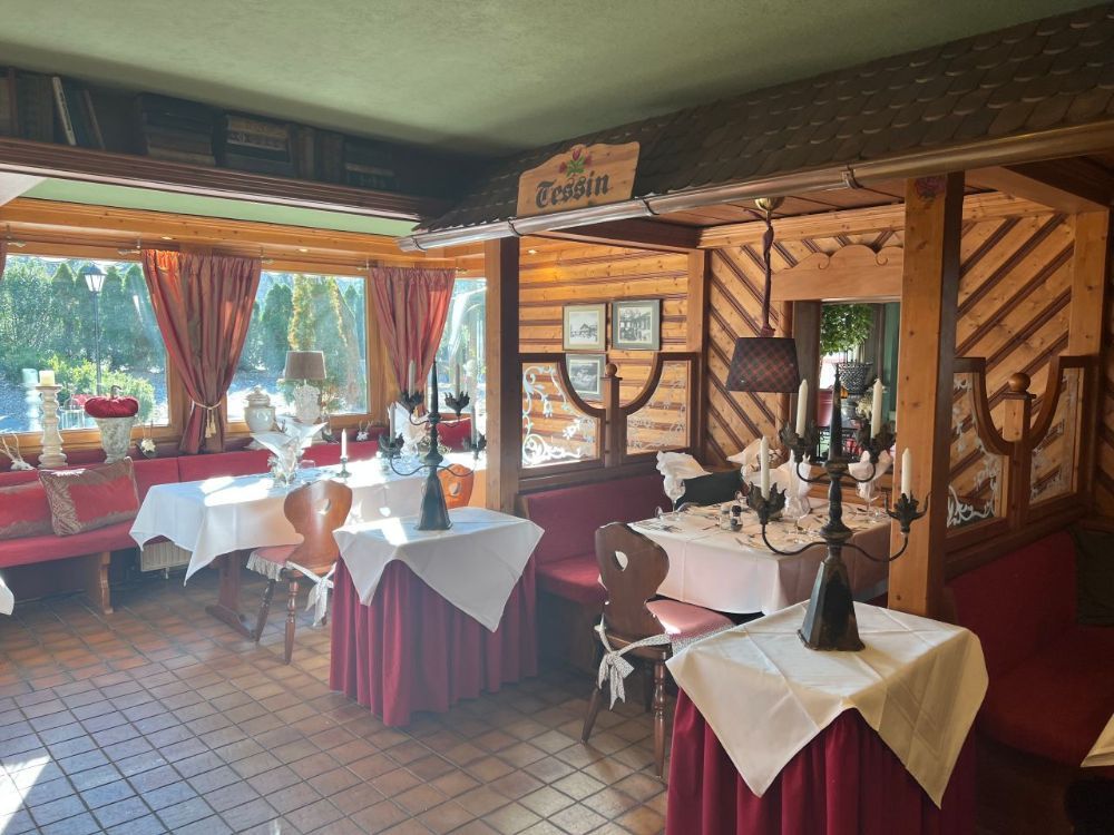 Innenansicht eines Restaurants mit Holzwänden, gedeckten Tischen und einem Fenster mit Blick ins Grüne.