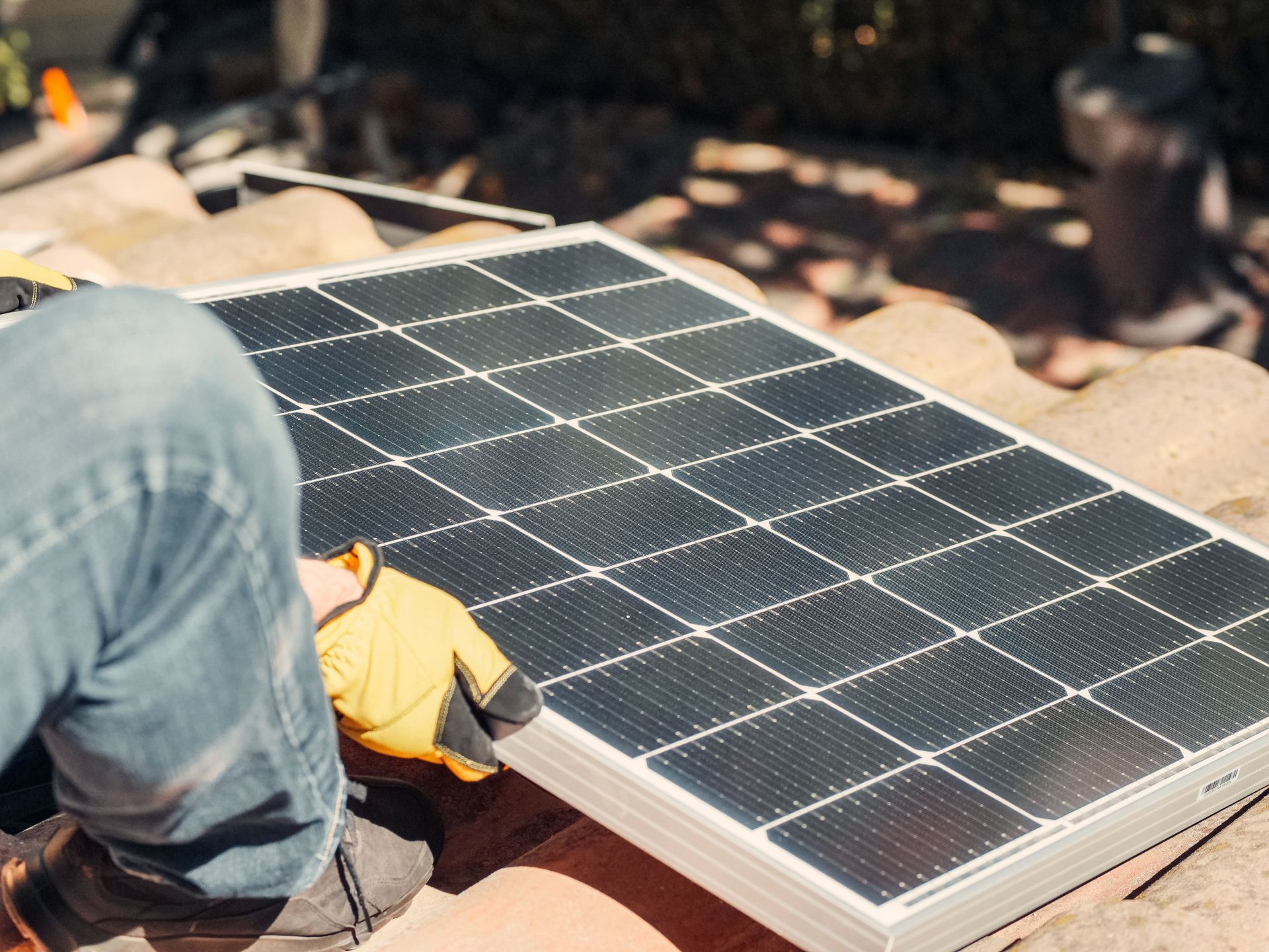 Un ouvrier installe un panneau solaire sur un toit, en plein air